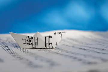Paper boat made of musical score sheet in blue background