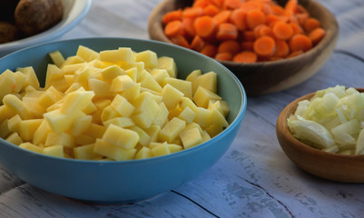 Bowls with chopped fresh and raw vegetables in small pieces prepared for veggie soup cooking