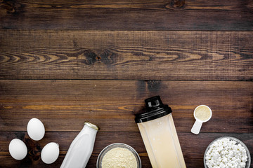 Protein diet for the athlete Scoop of protein near shaker, milk, eggs, cottage cheese on dark wooden background top view copy space