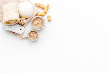 Natural cosmetics for skin care. Body scrub with peanut. White background top view copy space