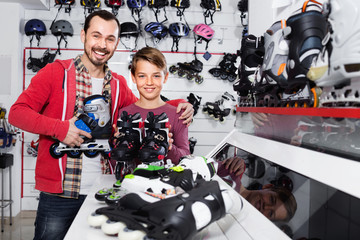 Father and son showing roller-skates they bought in sports store