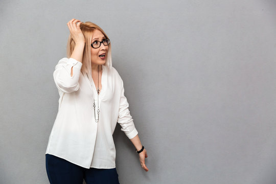 Confused middle-aged blonde woman in shirt and eyeglasses