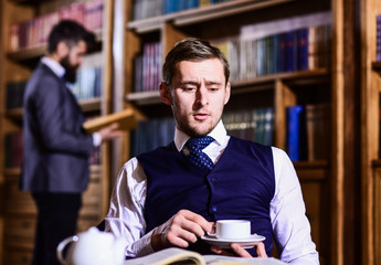 Blue blood concept. Young men with antique bookshelves on background