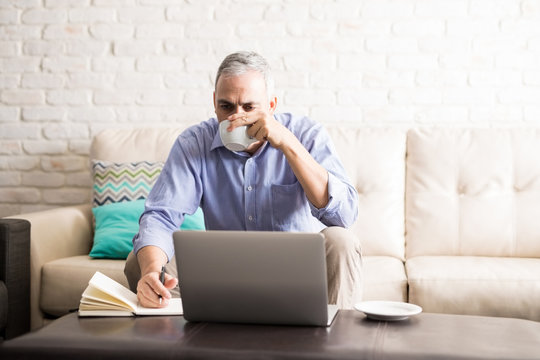 Middle Aged Man Drinking Coffee While Working From Home