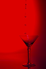 Martini glass high key photo in studio with red tint and water plash