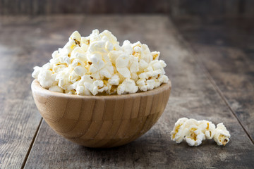 Popcorn in bowl on wooden table. 

