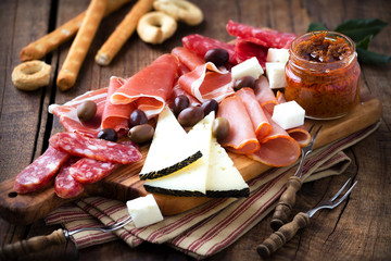 Image of Cured meat and cheese platter of traditional Spanish tapas - chorizo, salsichon, jamon serrano, lomo and slices of goat cheese - served on wooden board with olives and bread sticks printed on Printed Glass Basin Splashbacks