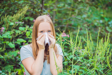Young woman sneezes because of an allergy to ragweed