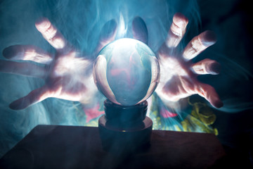 A fortune teller works in a dark room with a crystal ball
 - obrazy, fototapety, plakaty