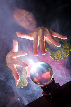 A fortune teller works in a dark room with a crystal ball
