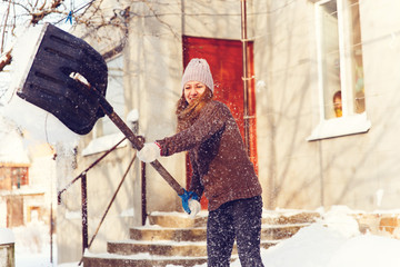 Fototapeta na wymiar Woman shoveling and removing snow in front of her house in the suburb.