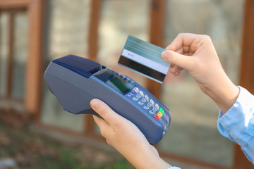 Woman using bank terminal for credit card payment outdoors