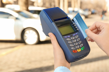 Woman using bank terminal for credit card payment outdoors