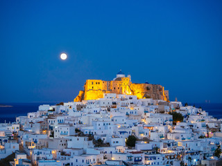Chora of Astypalaia in blue hour with the full moon rising behind the enlightened fortress