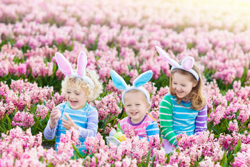 Kids on Easter egg hunt in blooming garden.