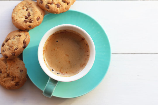 Coffee in a turquoise mug and cookies on a white table the top view