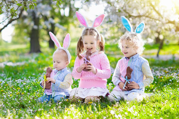 Garden Easter egg hunt. Kids eat bunny chocolate.