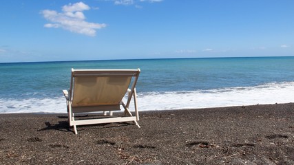 Black pebble beach with lounge chair