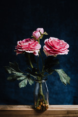 Artificial peony plant in bottle on dark background