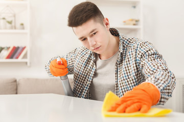 Young man cleaning home with detergents
