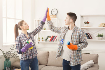 Couple giving five to each other holding cleaning equipment