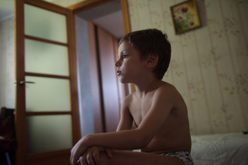 Fototapeta premium lonely sad little kid sitting in the room with no clothes on