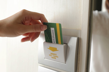 Hand insert room keycard on hotel door.