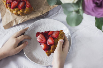 Home made strawberry pie in child's hands on dinning table
