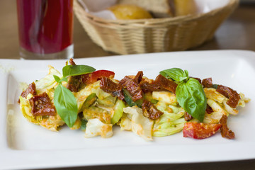 Raw food salad of fresh vegetables and sun-dried tomatoes in a white plate on the table