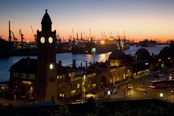Silhouette of the clock tower of the famous Hamburger Landungsbruecken with commercial harbor and Elbe river, St. Pauli district, Hamburg after sunset.