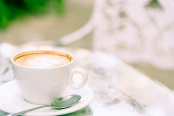 A white cup of coffee and laptop ready to working in the morning with relaxing and yellow lighting bokeh background.