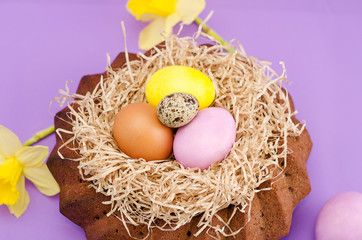 Easter still life, Easter cake, chicken and quail eggs, on a violet  background.