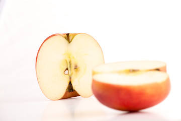 aufgeschnittener Apfel - zwei Apfelhälften eines rot orangen Apfels, Apfelkerne sichtbar, eine Hälfte liegt die andere steht