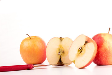 zwei Äpfel und ein geteilter Apfel mit Messer vor weißem Hintergrund