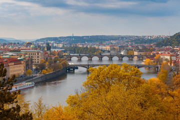 Fototapeta na wymiar Scenic aerial view of the Old Town architecture and bridge over Vltava river in Prague, Czech Republic. Trees of the park at the foreground, fall time