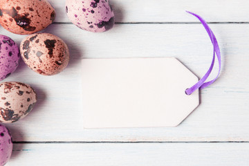 Painted eggs with white tag on wooden background.