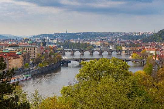 Scenic aerial view of the Old Town architecture and bridges over Vltava river in Prague, Czech Republic. Trees of the park at the foreground.
