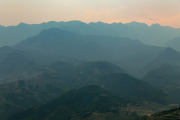 Layers of silhouette mountains with orange sky and sky in the dusk in the dusk in Sa Pa, Vietnam.