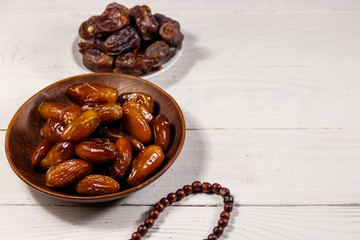 Dates fruit and rosary on white wooden table