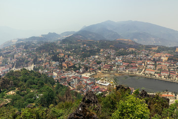 Sa Pa landscape with city, mountains, fog and trees the view from above from Sam Bay Cloud Yard in summer at Ham Rong Mountain Park in Sa Pa, Vietnam.