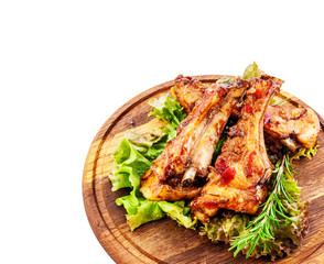 Fried pork ribs on a round wooden substrate with greens seasoning. Clipping path.