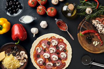 Raw pizza ingredients on black texture table background