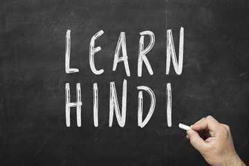 Human hand writing text on blackboard: Learn hindi