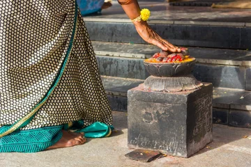 Fotobehang Indian woman in traditional saree bows the feet statue at the entrance of Ganesh Temple in Gokulam, Mysore, India. Hinduism religion venerate, adore, worship concept © Josu Ozkaritz