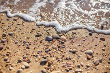 Fototapeta na wymiar pebble stones on the sea beach, the rolling waves of the sea with foam