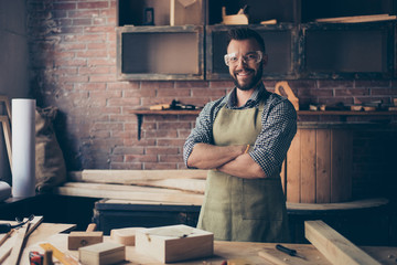 Satisfied cheerful joyful smiling with stylish hairdo bearded wearing apron woodmaster is standing...