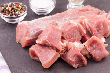 Raw pork tenderloin close-up and chopped pieces of meat for extinguishing