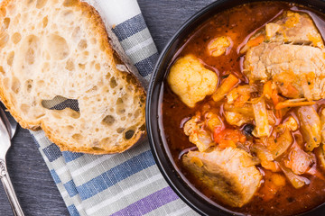 Braised meat with vegetables in a black bowl close-up