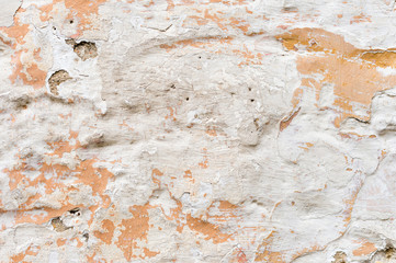 Textured grunge background. Volumetric plastered wall with a multilayer cracked coating. Orange chips on the whitewashed wall. Grunge texture with a deep pattern