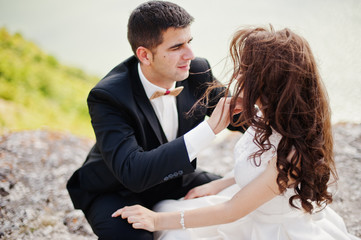 Wedding couple at breathtaking landscape with rock and lake.